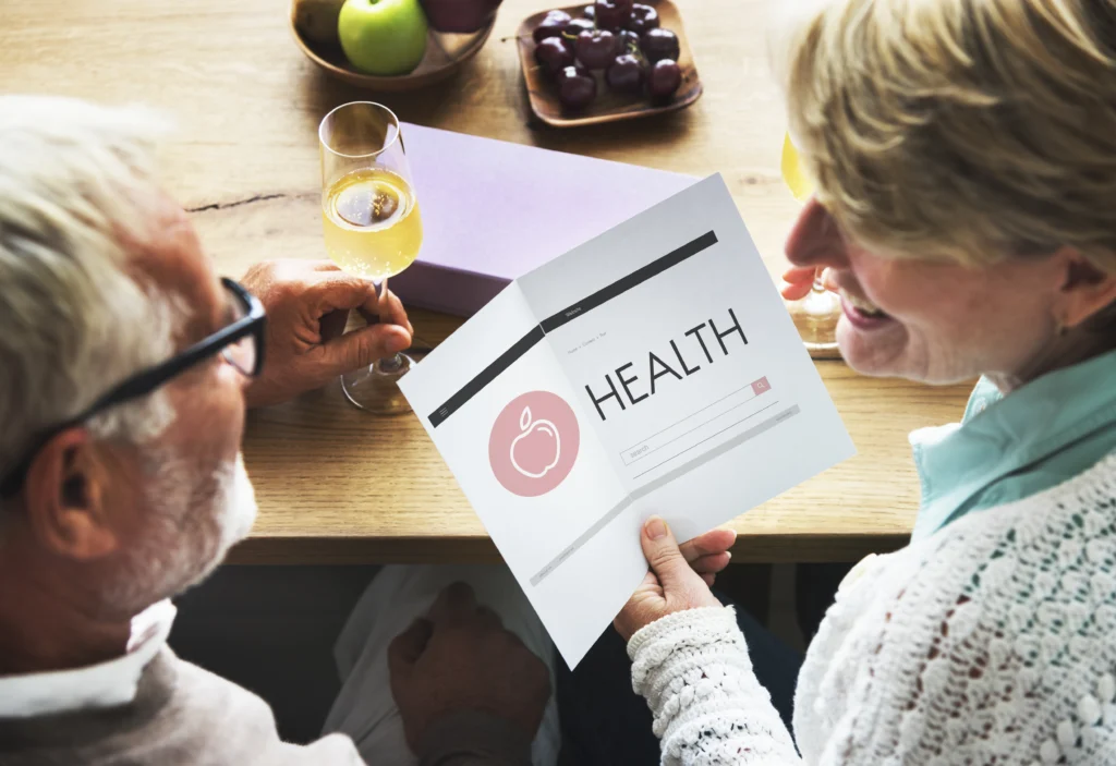 womand and older man at a table with wine and olives reviewing a health report