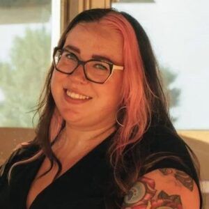 Caite Dahl woman with long hair and glasses smiling at camera